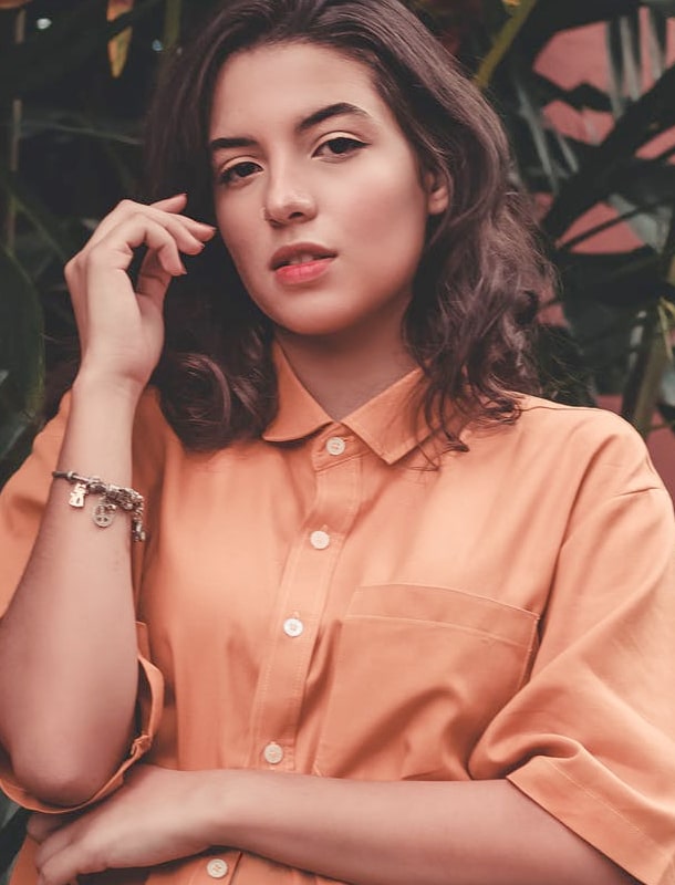 caucasian woman in orange shirt with short, brown hair posing