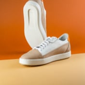 pair of white and brown sneakers with left sneaker positioned vertically