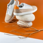 pair of white and brown sneakers with right sneaker placed on top of two stones