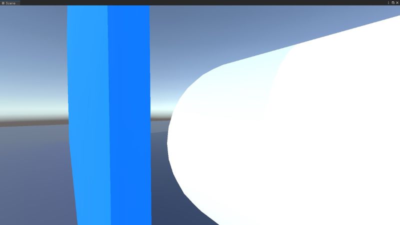 A white capsule beside a blue wall in Unity.